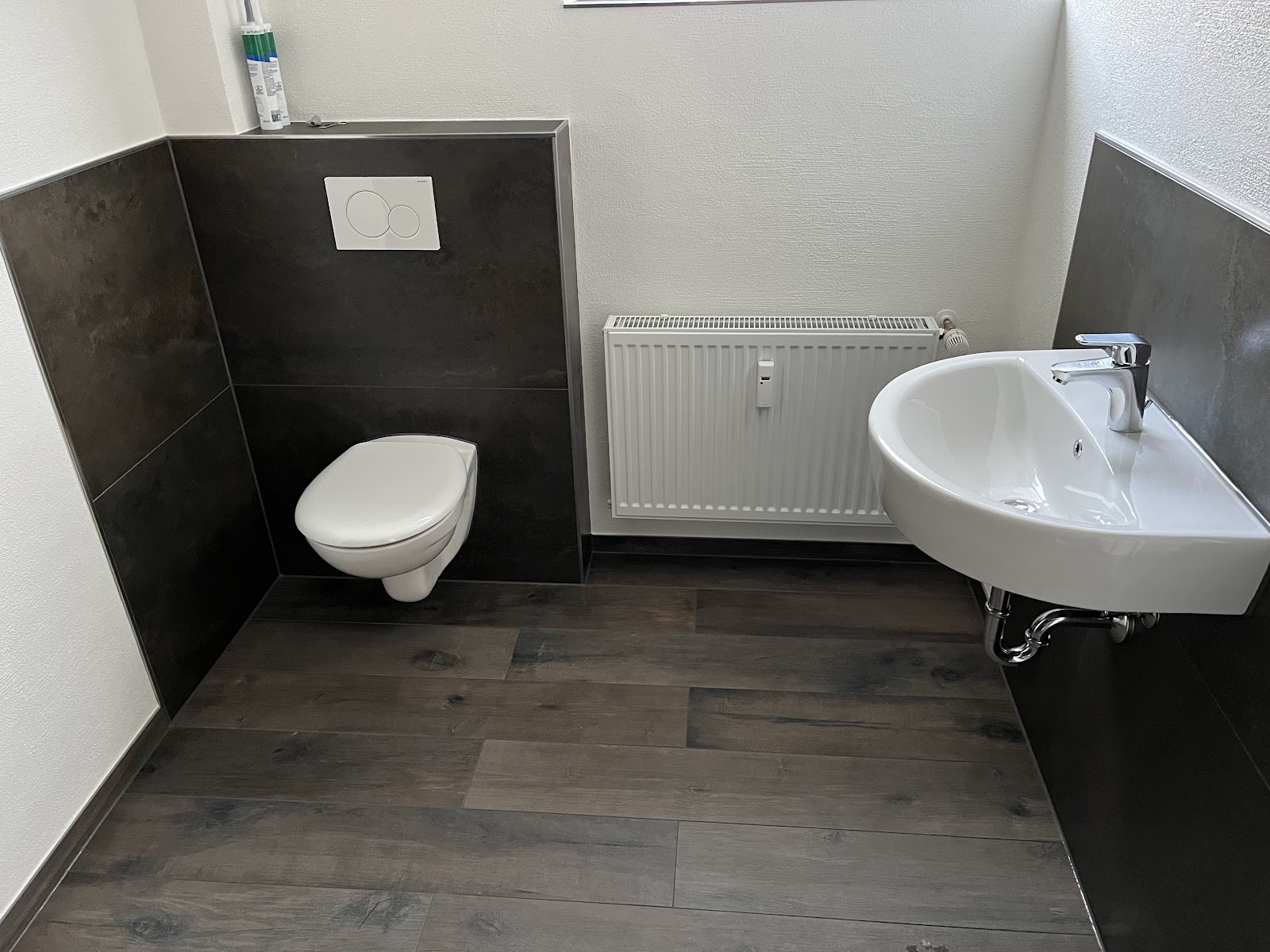 Gäste-WC mit dunklen Fliesen und schwebendem WC