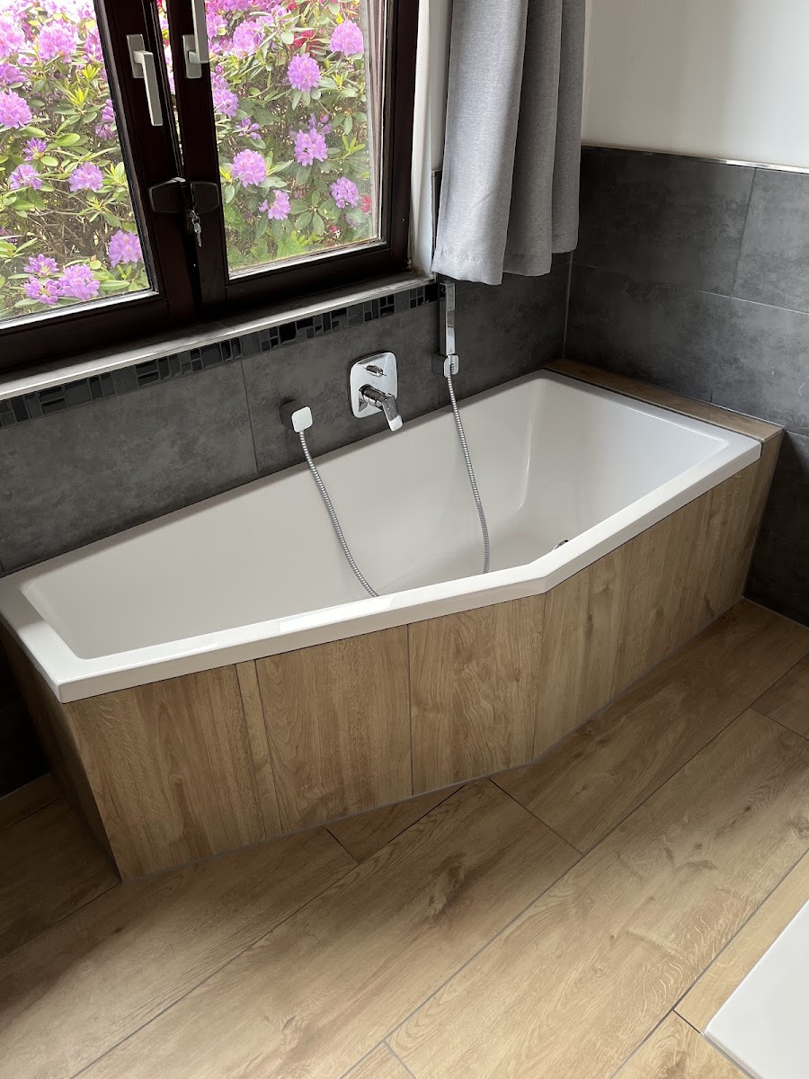 Badewanne mit Holzoptik-Verkleidung vor Fenster